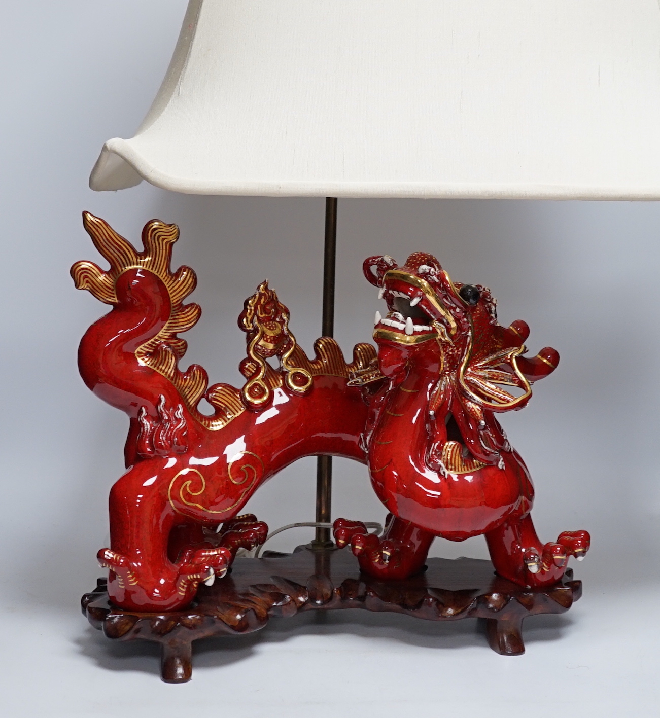 A modern Chinese red and gilt glazed ceramic 'dragon' table lamp on carved wood stand with shade, total height 68cm